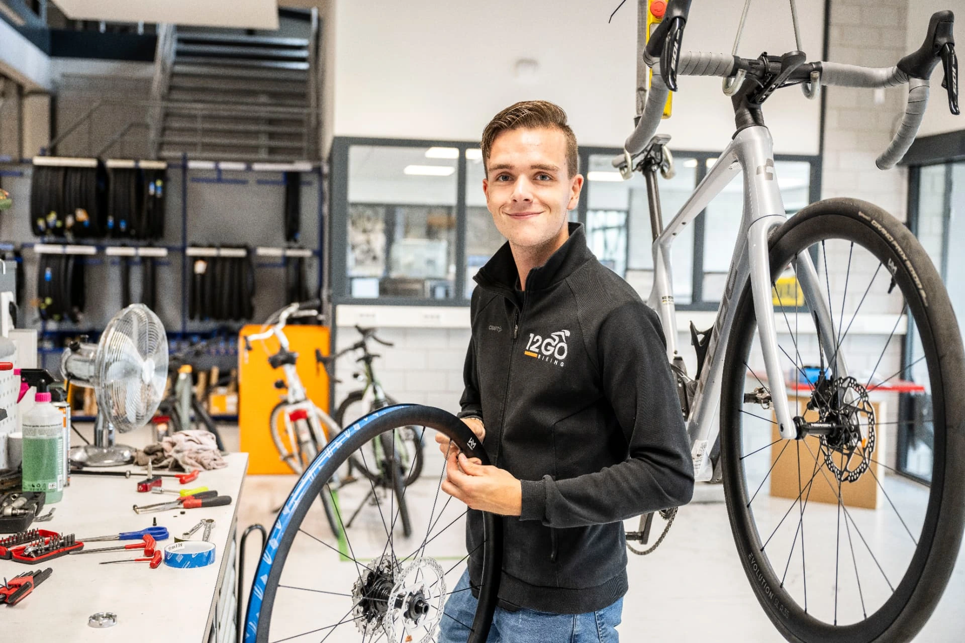 Fietstechnicus legt een binnenband in een racefietswiel in de werkplaats van 12GO Biking